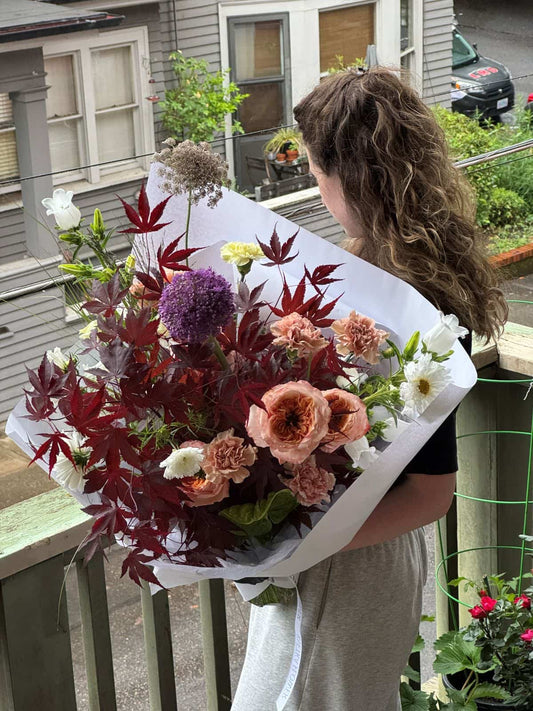 Extra large seasonal bouquet with deep red Japanese maple foliage, peach carnations, garden roses and purple allium in white wrap, by Portland florist Kvetka Flower