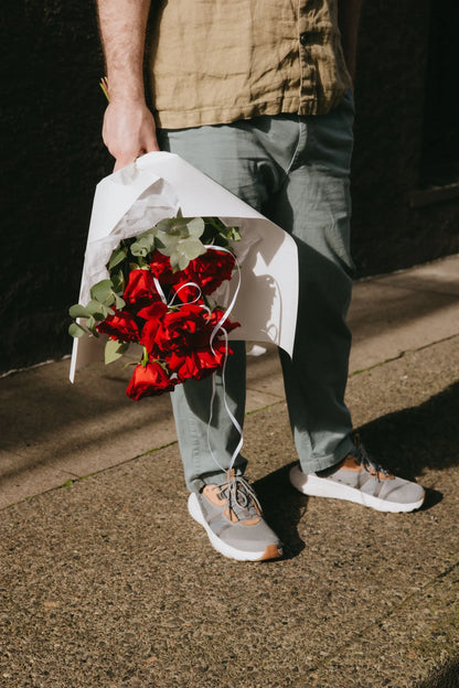 Dozen red roses bouquet with eucalyptus wrapped in white paper for Valentine's Day