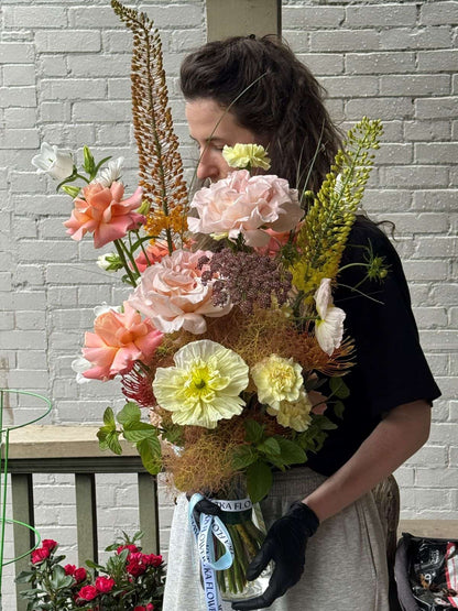 Florist holding the Aloha Aina tropical-inspired bouquet in a glass vase with Kvetka ribbon, peach roses and yellow poppies, by Portland florist Kvetka Flower