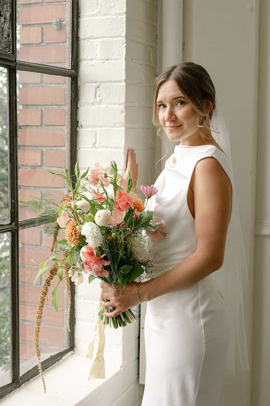 Bride standing near window with soft bridal bouquet at Tendue Portland