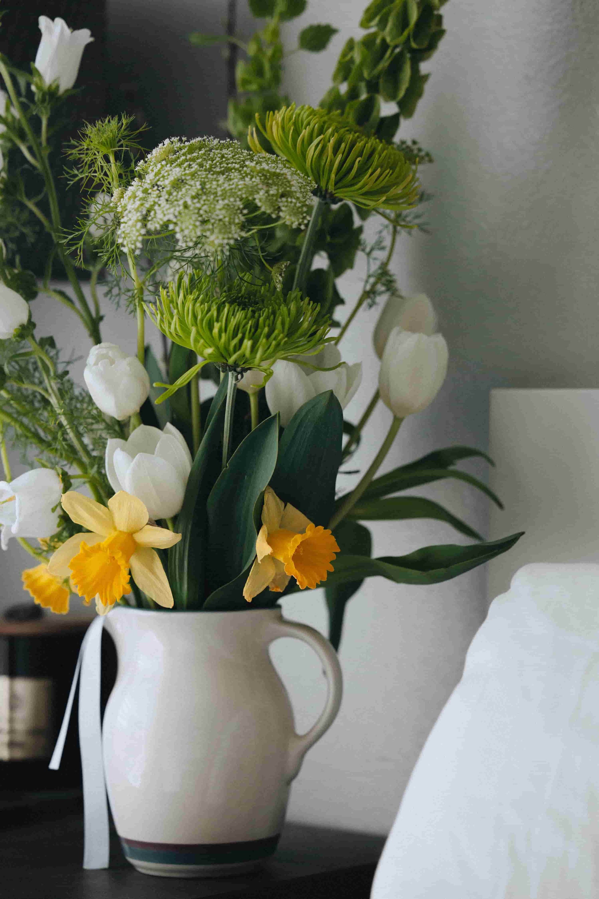 Spring flower bouquet on nightstand with tulips, bells of Ireland and daffodils – Portland flower subscription by Kvetka