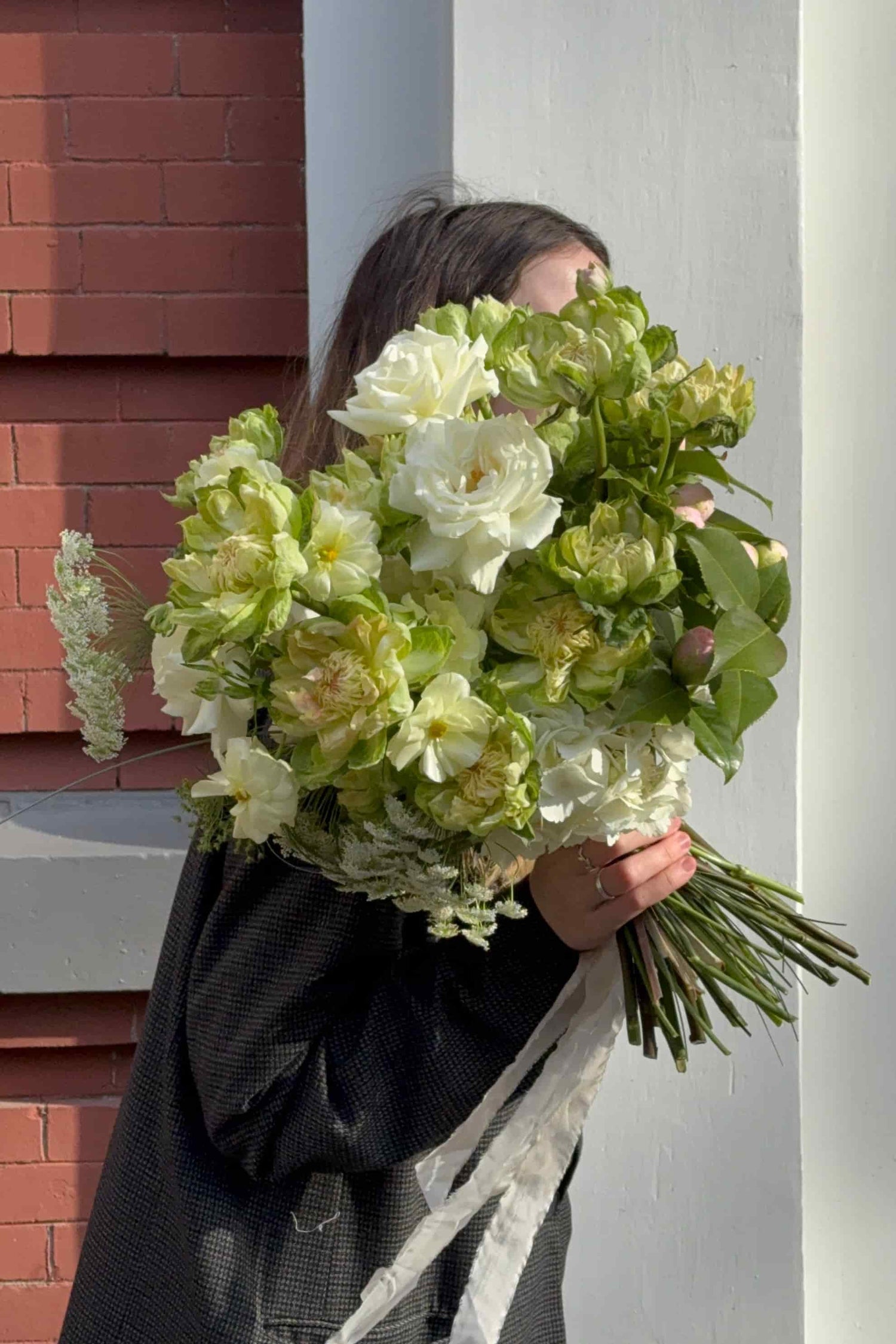 Person holding a large European-style hand-tied bouquet of white and green veggie roses and butterfly ranunculus, by Kvetka Flower, Portland florist