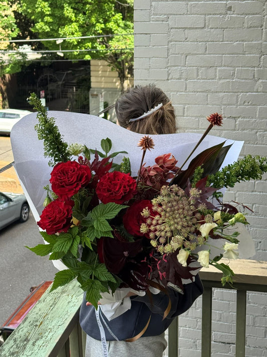 Fresh seasonal summer bouquet with red roses, orchids, anthurium, sweet pea, and raspberry greenery by Kvetka Flower Portland
