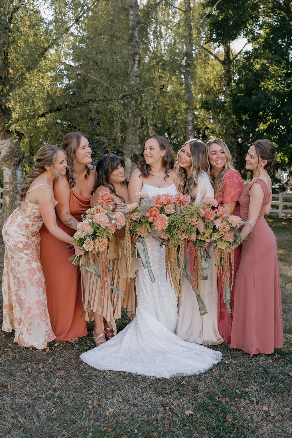 Candid moment of bridesmaids featuring a rust wedding color scheme and fall florals.