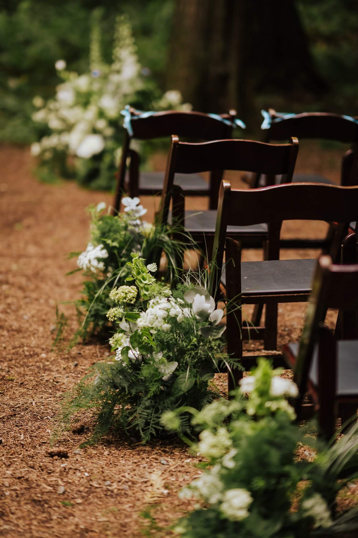 Aisle flowers with white blooms and green foliage at forest ceremony site – by Kvetka Flower, Portland OR
