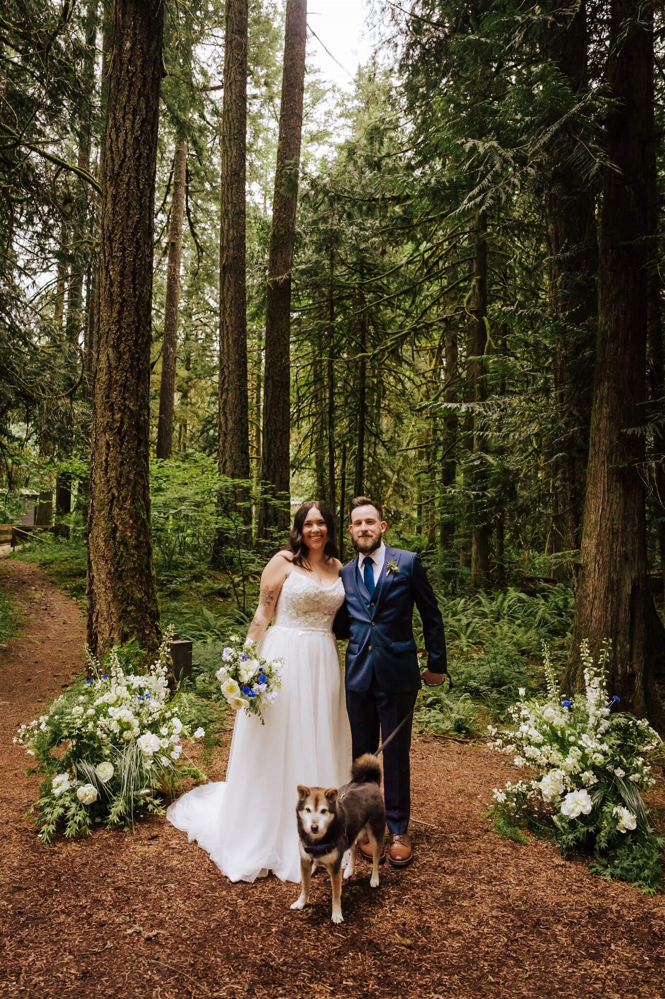 Bride smiling in the garden, holding her blue and white wedding bouquet – by Kvetka Flower, Portland OR
