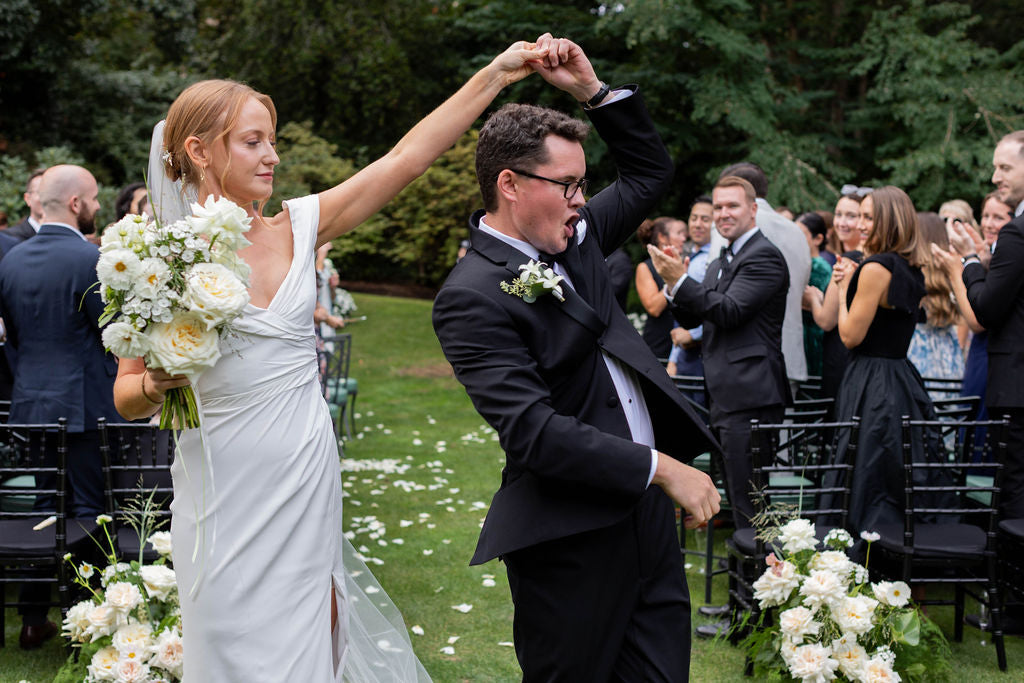 Bride twirling with white garden rose bouquet over rose petals at The Town Club Portland wedding by Kvetka Flower