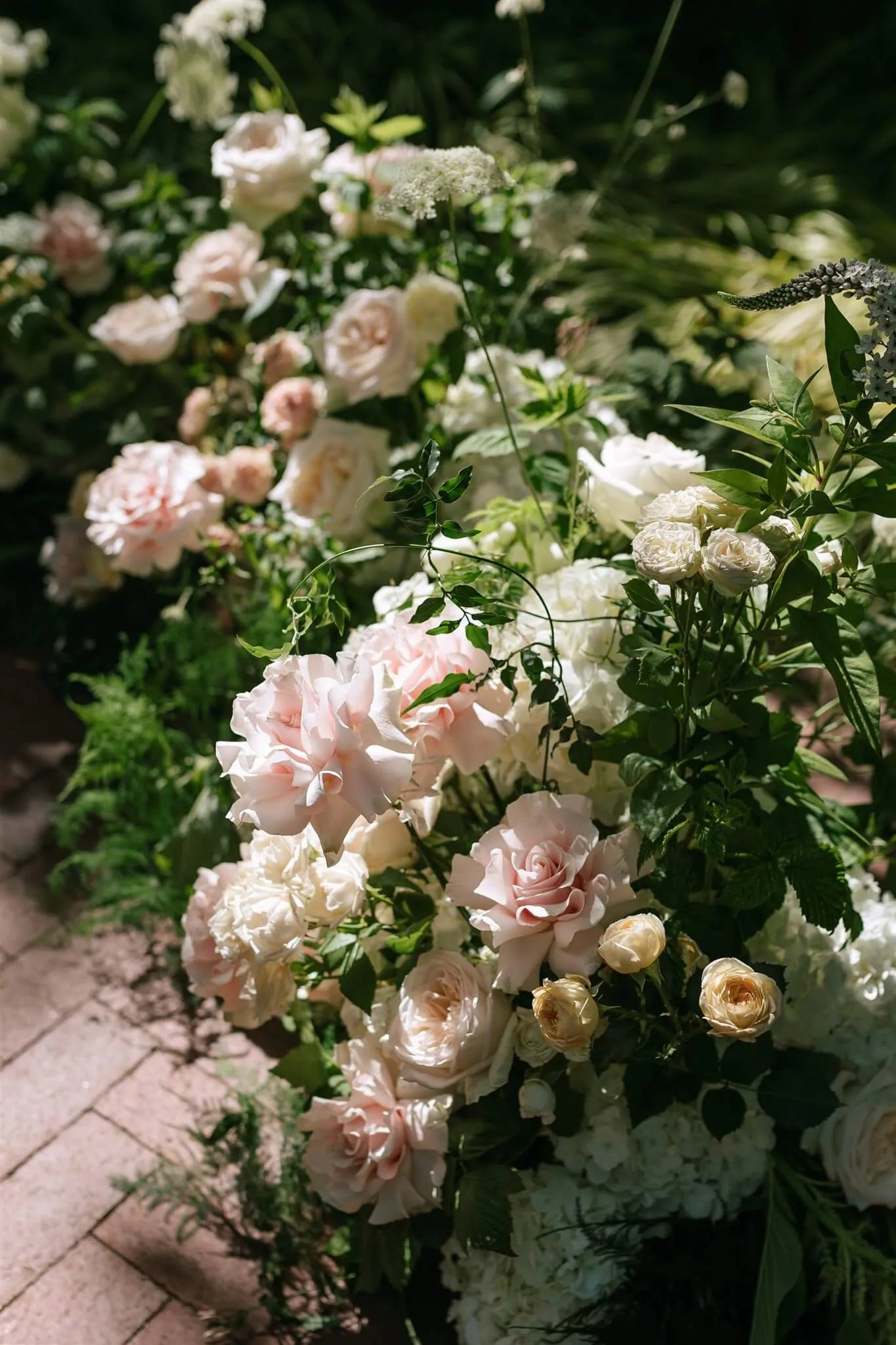 Close-up of ceremony ground arrangement with blush roses and white hydrangea by Portland wedding florist Kvetka Flower