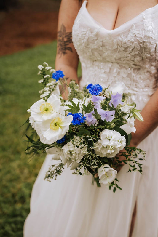 Close-up of groom’s boutonniere with greenery and white flowers on blue suit – by Kvetka Flower, Portland OR
