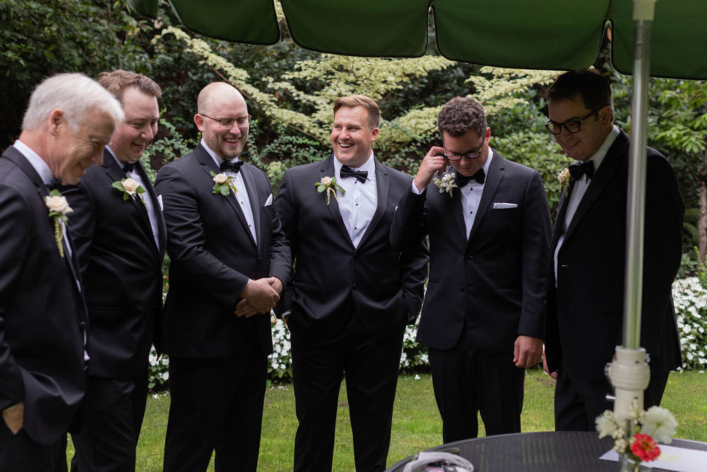 Groomsmen laughing wearing white rose and greenery boutonnieres at The Town Club Portland wedding, florals by Kvetka Flower