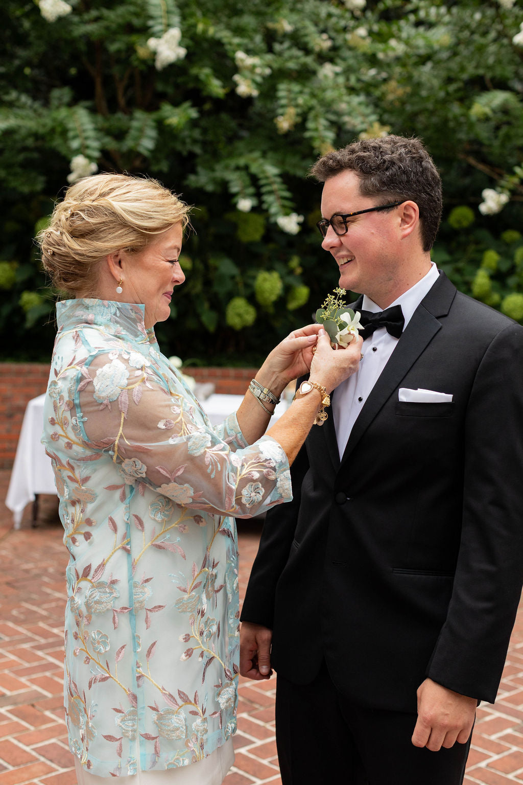 Mother of groom pinning white rose and seeded eucalyptus boutonniere at The Town Club Portland wedding by Kvetka Flower