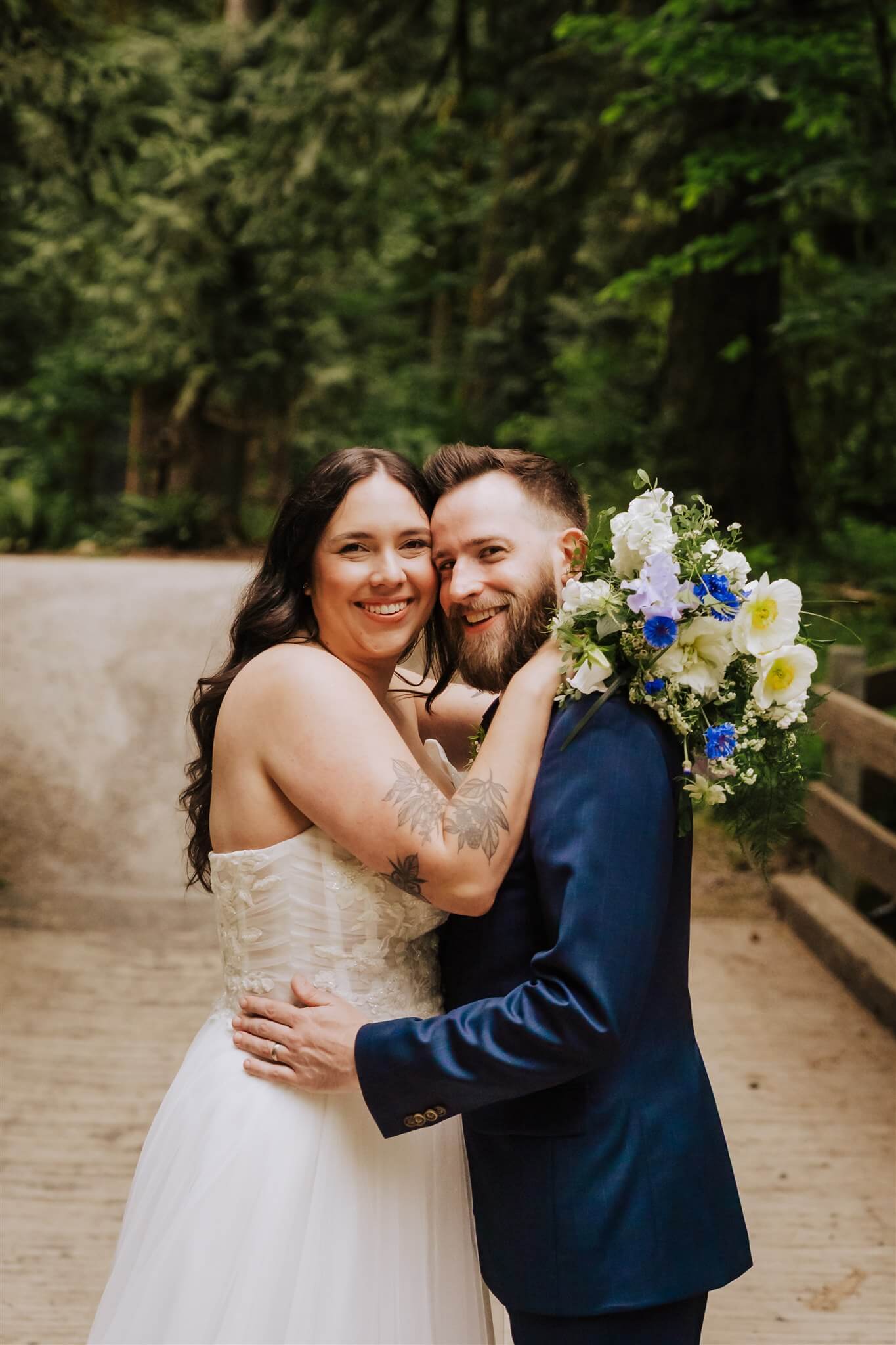 Close-up of bride and groom smiling with bridal bouquet over groom’s shoulder – by Kvetka Flower, Portland OR
