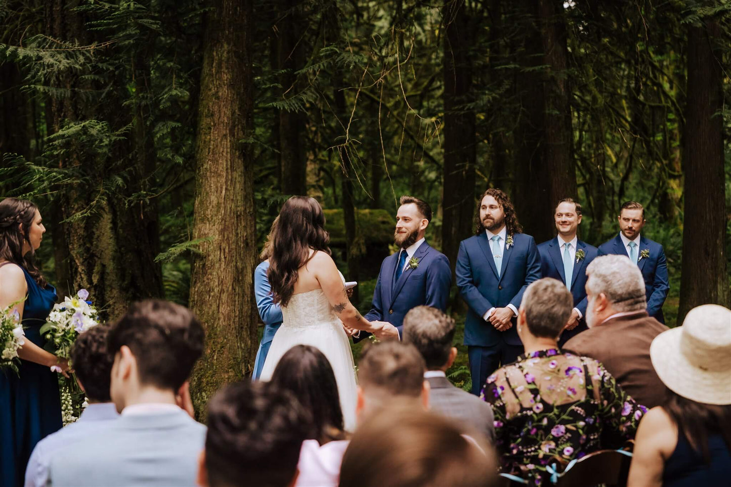 Bride reading vows to groom during ceremony with groomsmen in the background at Camp Colton – by Kvetka Flower, Portland OR
