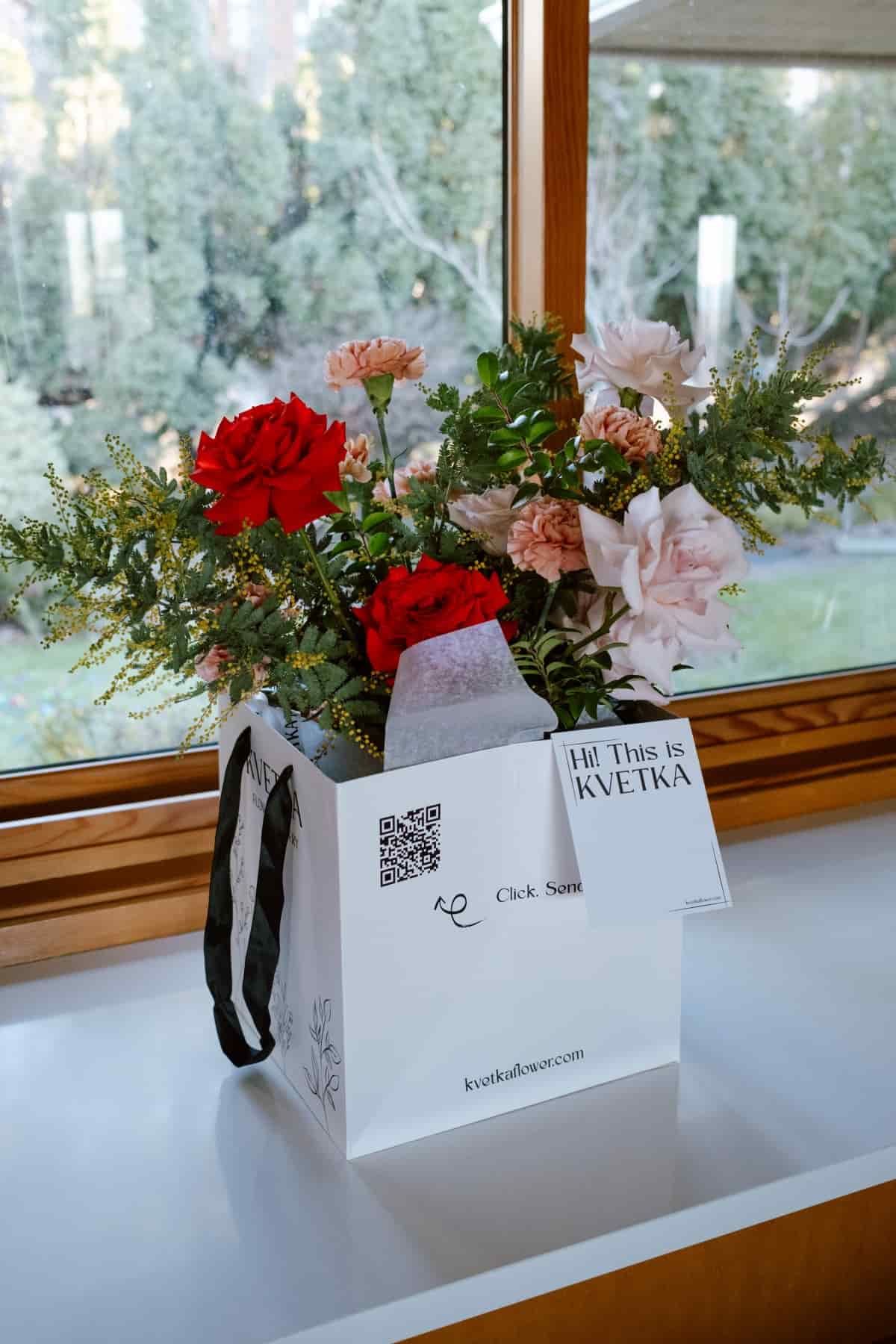 Branded white Kvetka signature flower box holding red and pink roses, carnations and mimosa, by Kvetka Flower, Portland florist