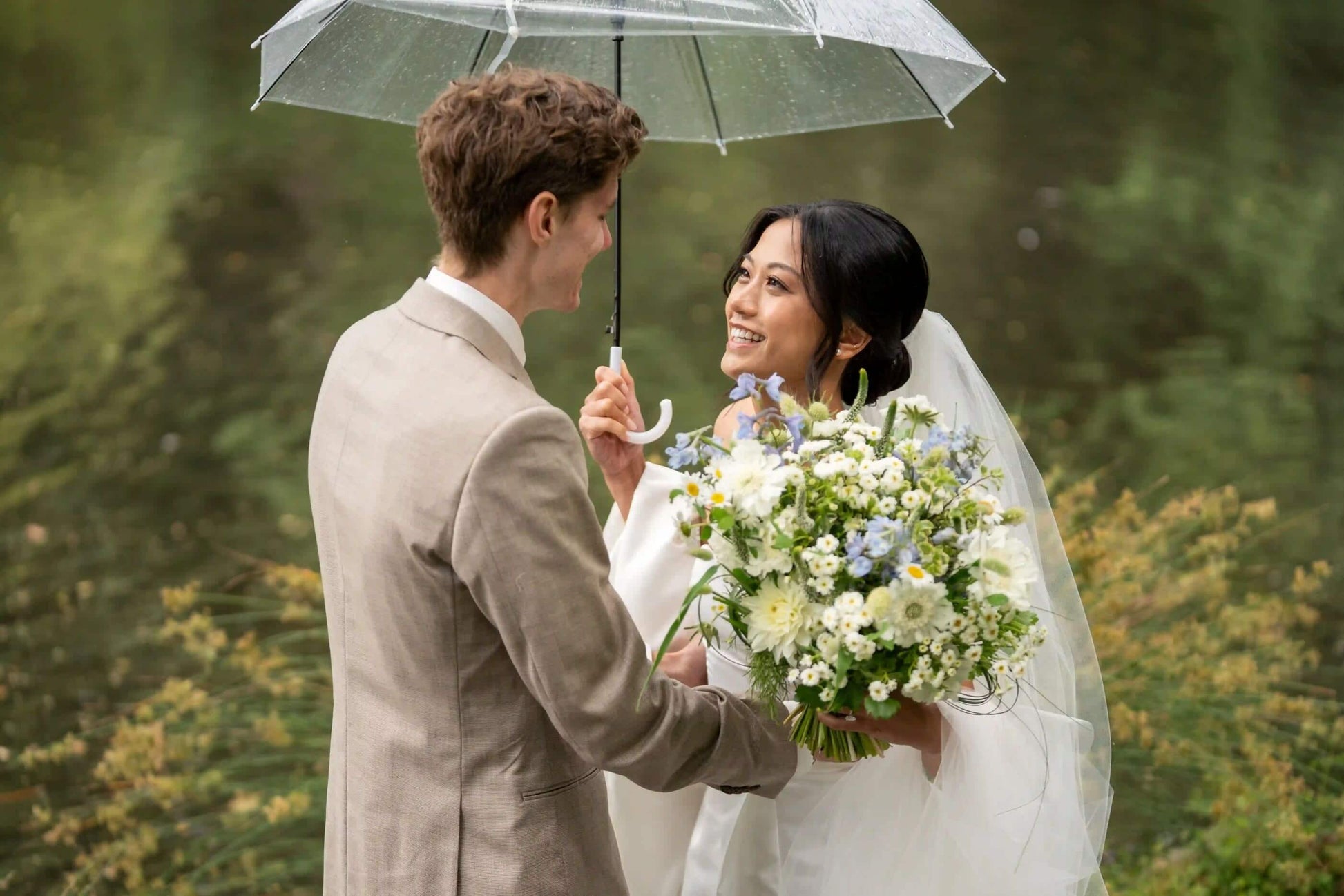 Bride holding an umbrella and smiling at groom with Kvetka Flower wedding bouquet in Portland, OR