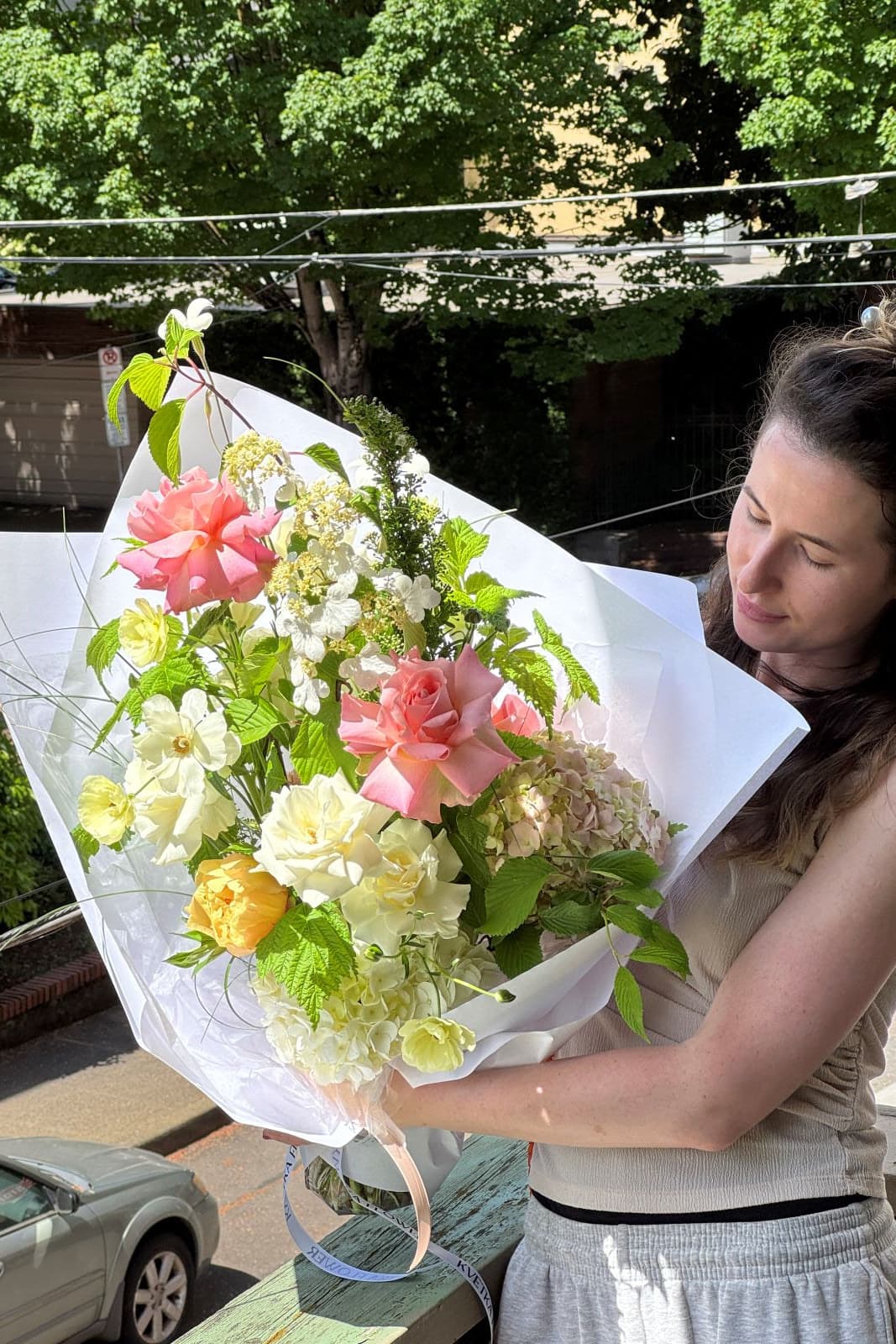 Woman holding Pink Acacia pink rose bouquet with yellow and white seasonal accents by Portland florist Kvetka Flower