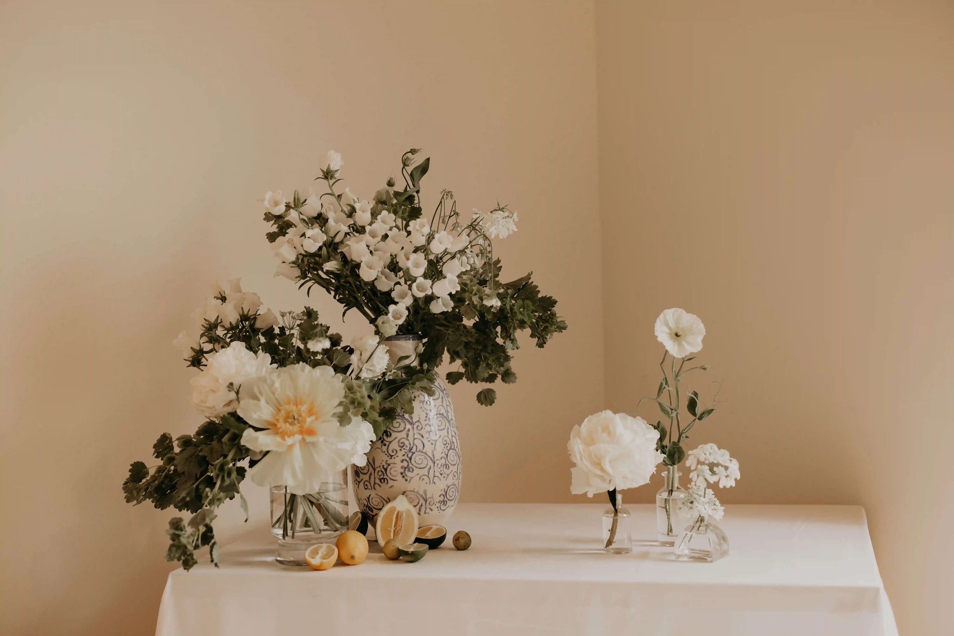 Wedding welcome table with white peonies, citrus fruits, and delicate florals – designed by Kvetka Flower, Portland OR